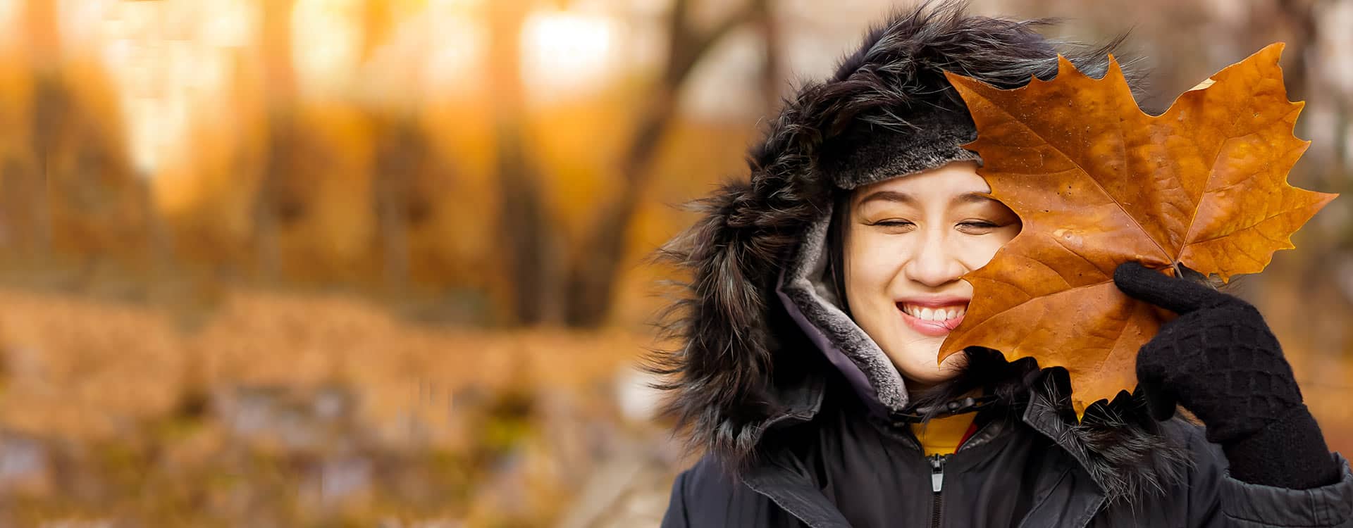 女人微笑着拿着枫叶